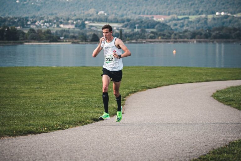 Coureur buvant de l'eau en pleine chaleur au RunMotion Coach Marathon de Chambéry, au bord du lac du Bourget